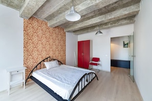 Un dormitorio con cama, armario, silla y escritorio.