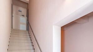 A staircase with a handrail, a light fixture on the wall, and a door at the top. - Ap Accent by Polo apartments (Kaunas)