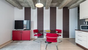 A modern kitchen with a dining area, a TV, and a microwave. - Ap Accent by Polo apartments (Kaunas)