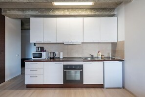 Una cocina moderna con armarios blancos, microondas, cafetera y lavavajillas.