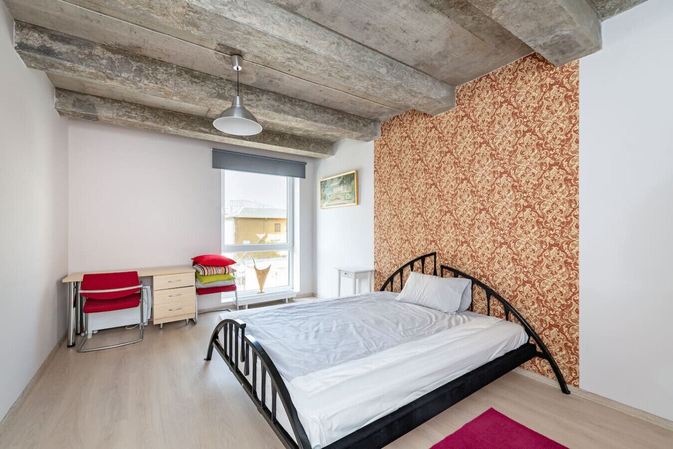 Een slaapkamer met een bed, een bureau, een stoel en een raam.