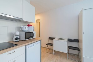 Una cucina compatta con forno a microonde, macchina del caffè e un piccolo tavolo con sedie.