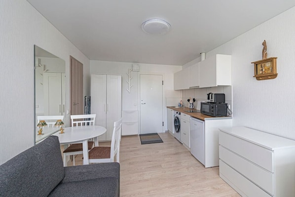 A compact living space with a kitchenette, a dining area, and a sofa.