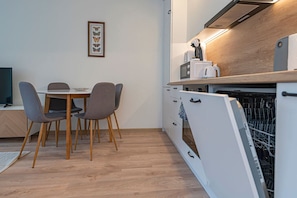 A compact kitchen with a dishwasher, a microwave, and a toaster on the counter. - Luminious ap w balcony by PoloApartments (Kaunas)