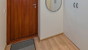 Ein Zimmer mit Holztür, einem kleinen Spiegel und einer Deckenleuchte.