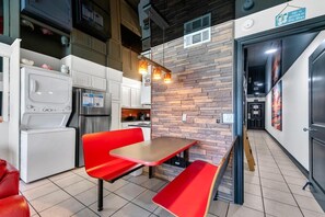 A compact kitchen with modern appliances, a red bench, and a stone accent wall.