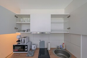 Une cuisine compacte équipée d’un four à micro-ondes, d’une bouilloire, d’un grille-pain et d’un évier.