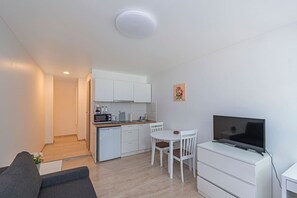 Un espace de vie compact comprenant un coin cuisine, un coin repas, un téléviseur et un canapé.