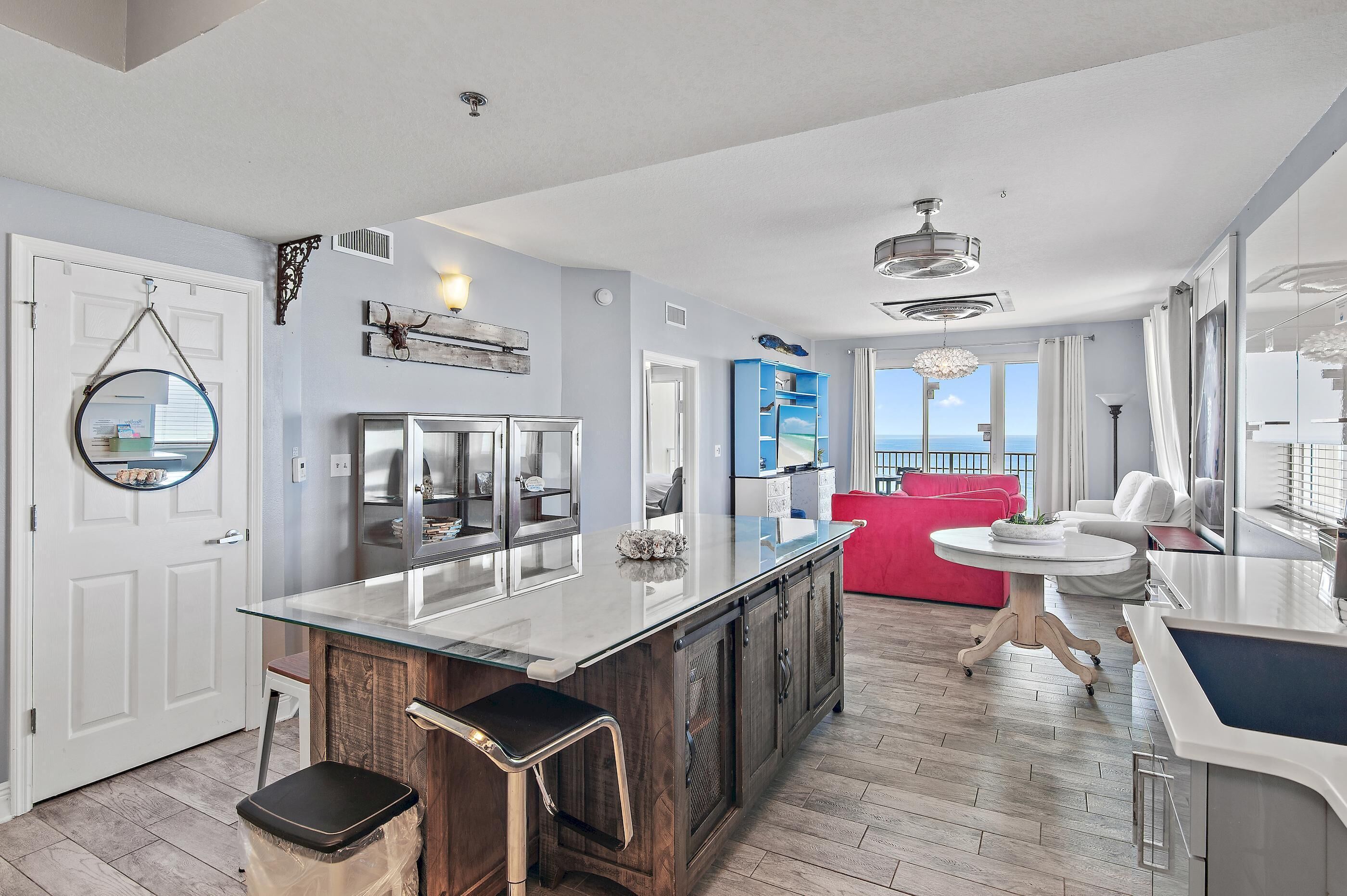 A modern kitchen with a central island, a dining area with a round table, and a view to the outside.