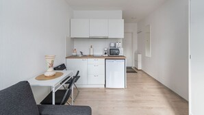 A compact kitchen with white cabinets, a microwave, a coffee maker, and a small refrigerator.