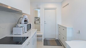 Een moderne keuken met een inbouwfornuis, magnetron en koffiezetapparaat.