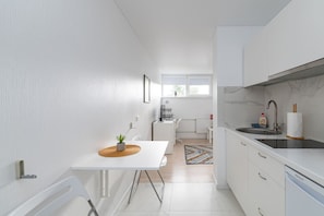 Une cuisine moderne avec des meubles blancs, un pare-feu en marbre et un lave-vaisselle encastré.