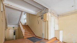 Een trap die leidt naar een plateau met een leuning, een deur en zichtbare elektriciteitskabels.