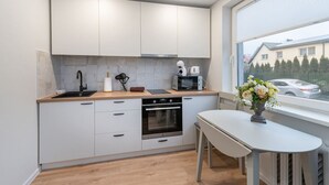 A modern kitchen with white cabinets, a wooden countertop, a built-in oven, and a dining area with a table and chairs. - Studio ap Sea by Polo Apartments (Kaunas)