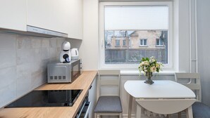 A compact kitchen with a microwave, toaster, and a small table with a vase of flowers. - Studio ap Sea by Polo Apartments (Kaunas)