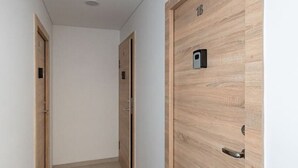 A hallway with wooden doors, a dark rug, and a light-colored floor.