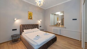 A bedroom with a large bed, a round ceiling light, a mirror, and a radiator.