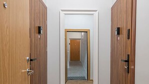 A hallway with wooden doors, a mirror, and a tiled floor.