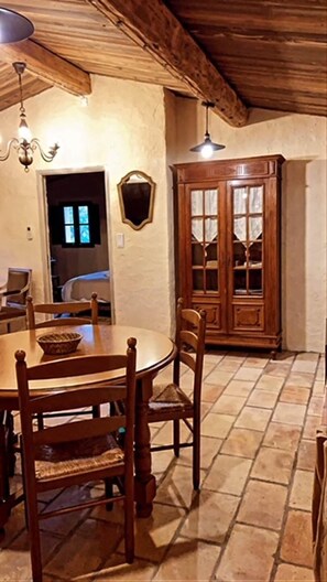 Un coin repas avec une table et des chaises en bois, un lustre et un grand meuble en bois doté de portes en verre.