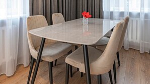 Un comedor con una mesa redonda, cuatro sillas y un florero con flores rojas.