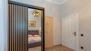 Un dormitorio con cama, armario, puerta y una lámpara fijada a la pared.