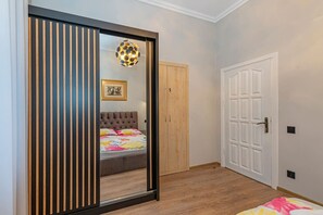 Une chambre à coucher comprenant un lit, une armoire, une porte et un luminaire fixé au mur.