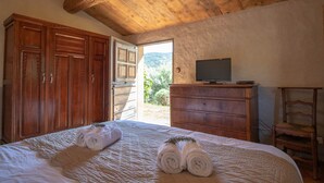 Un dormitorio con techo de madera, una cama con toallas dobladas, un aparador y un televisor encima.