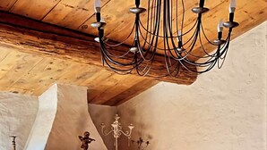 Un interior rústico con chimenea de piedra, vigas de madera en el techo y una araña.