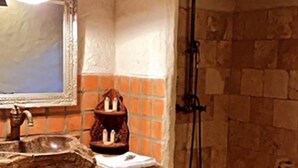 Un baño rústico con ducha de piedra, tocador de madera y salpicadero de azulejos.