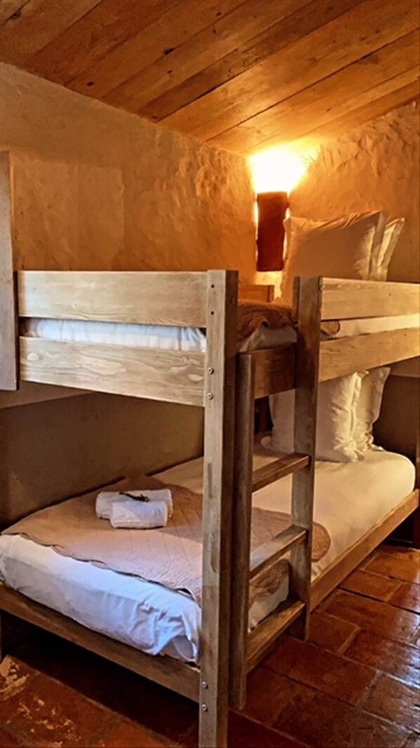 Una cama litera con estructura de madera y ropa de cama blanca.