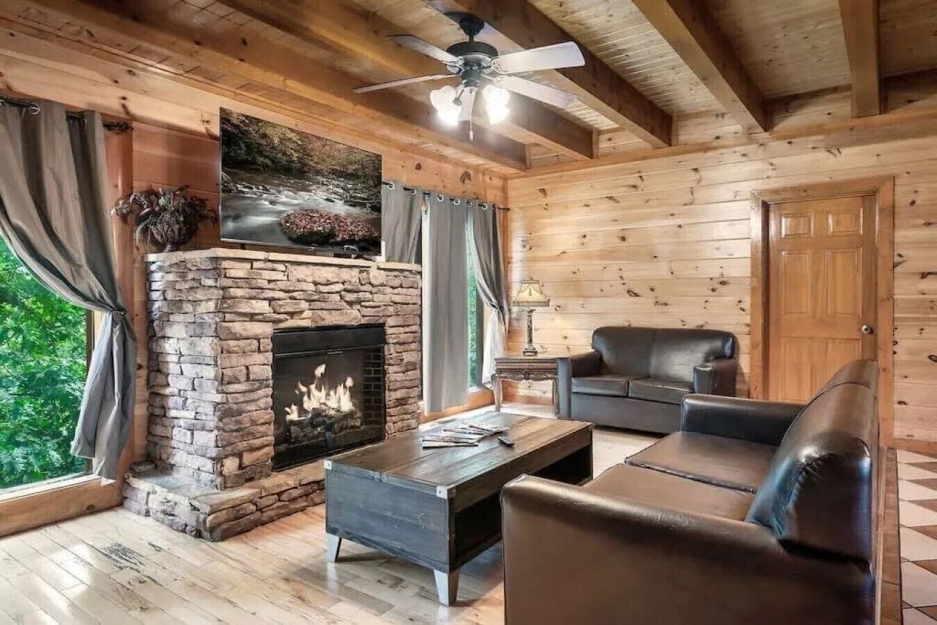 Un intérieur de chalet chaleureux avec une cheminée en pierre, des meubles en cuir et des murs en bois.
