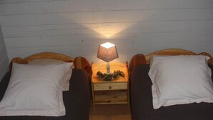 Une chambre avec deux lits simples, une table de chevet avec une lampe et un petit objet décoratif posé sur la table de chevet.