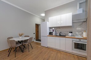A compact kitchen with white cabinets, a wooden countertop, and a dining area with a table and chairs.