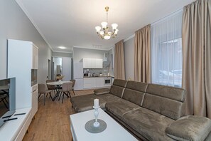 A modern living room with a sofa, a dining area, a kitchen, and a TV.