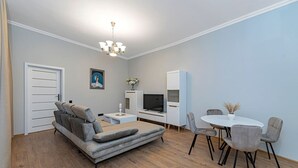 A modern living room with a sofa, TV, dining table, and chairs. - The Comfort Ap 3 by Polo Apartments (Kaunas)
