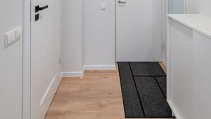 A narrow hallway with a wooden floor, white walls, and a door at the end. - Studio Ap Flora by Polo Apartments (Kaunas)