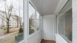 A narrow corridor with large windows, white brick walls, and a wooden floor. - Studio Ap Flora by Polo Apartments (Kaunas)
