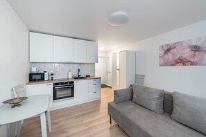 Een knus woongedeelte met kitchenette, een eethoek en een bank.