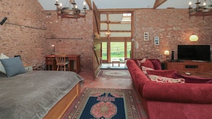 A cozy room with a bed, a red sofa, a TV, and a desk. - The Barn (Bridgwater)