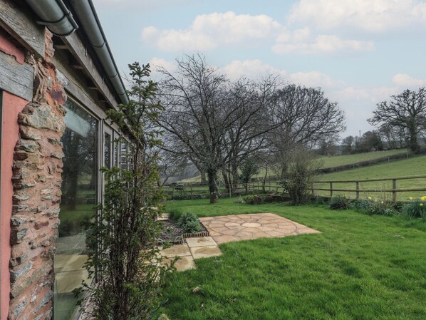 A stone pathway leading to a house with a brick wall and a glass door.
