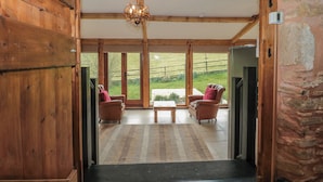 A spacious room with wooden beams, a skylight, and a view of the outdoors. - The Barn (Bridgwater)