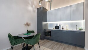 A modern kitchen with grey cabinets, a round dining table with green chairs, and a built-in oven.