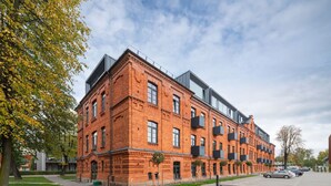 A red brick building with multiple floors, large windows, and balconies.