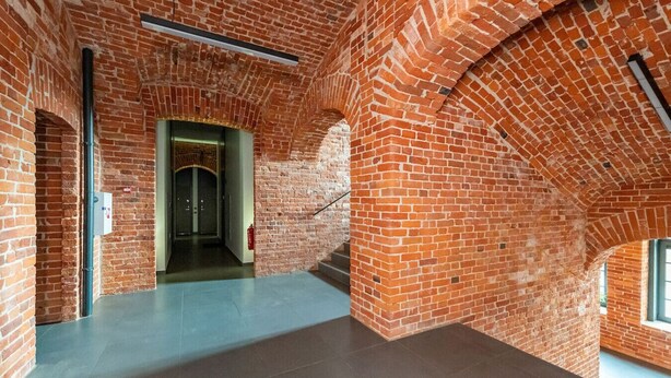 A spacious interior with exposed brick walls, a central staircase, and a modern, minimalist design.
