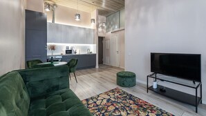 A modern living room with a green sofa, a flat-screen TV, and a patterned rug.