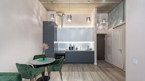 A modern kitchen with grey cabinets, a round table with chairs, and pendant lighting.