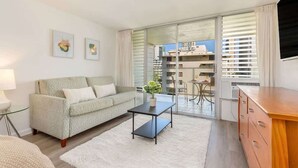 Un salon moderne avec un canapé, une table basse et une vue sur un balcon aménagé en coin repas.