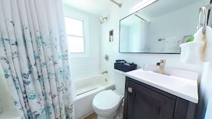Een badkamer met een bad, toilet en een wastafel met spiegel erboven.