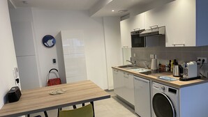 Una cocina moderna con armarios blancos, horno empotrado, lavabo y lavadora.