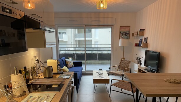 Una cocina moderna con comedor, sofá y televisor.